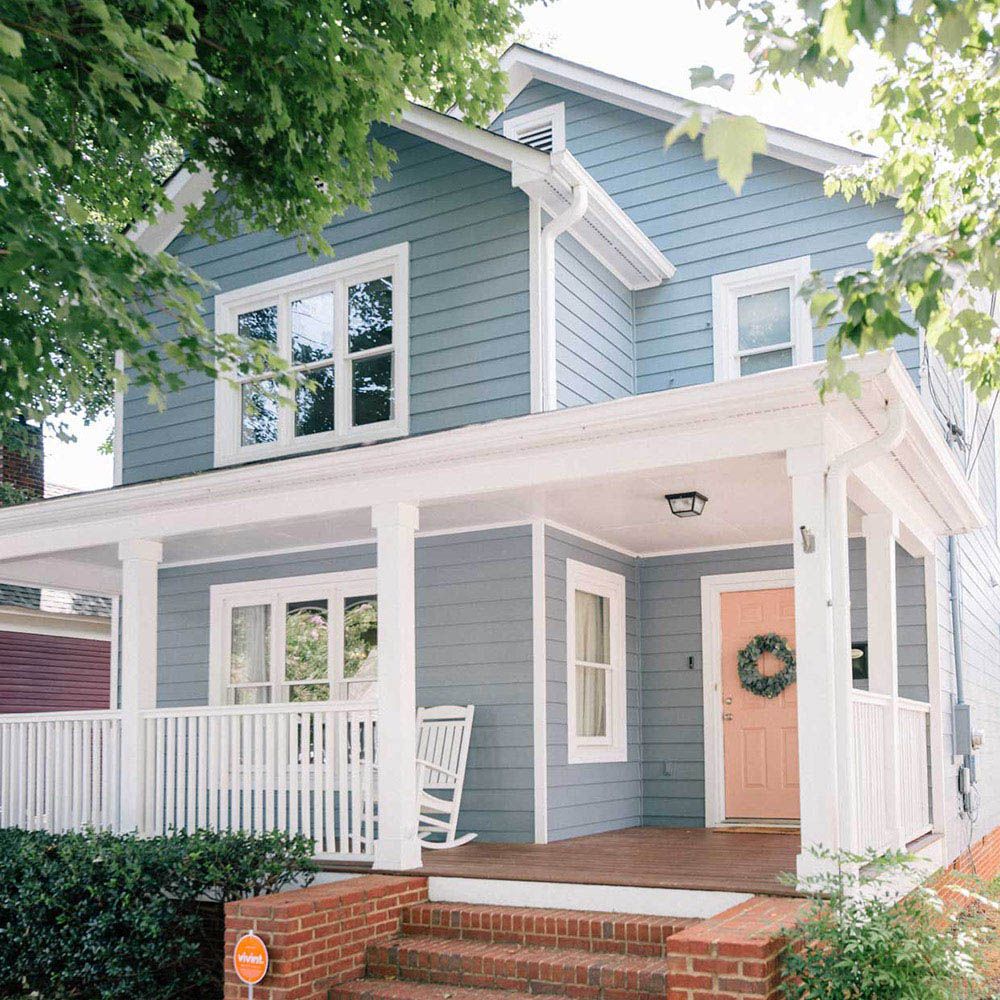 Light blue house with white trim and a red door wreath